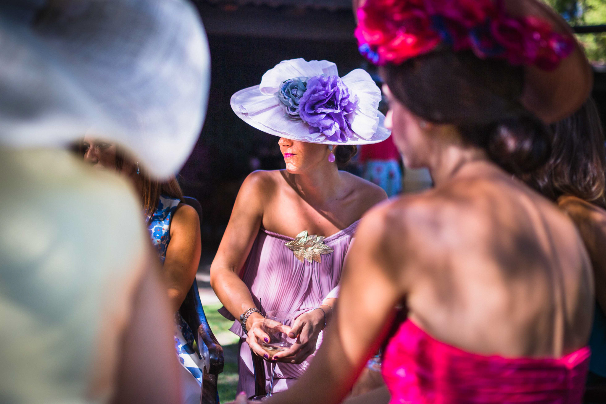 Des invitées en chapeaux fleuris échangent pendant le cocktail de mariage en fin d'après-midi.