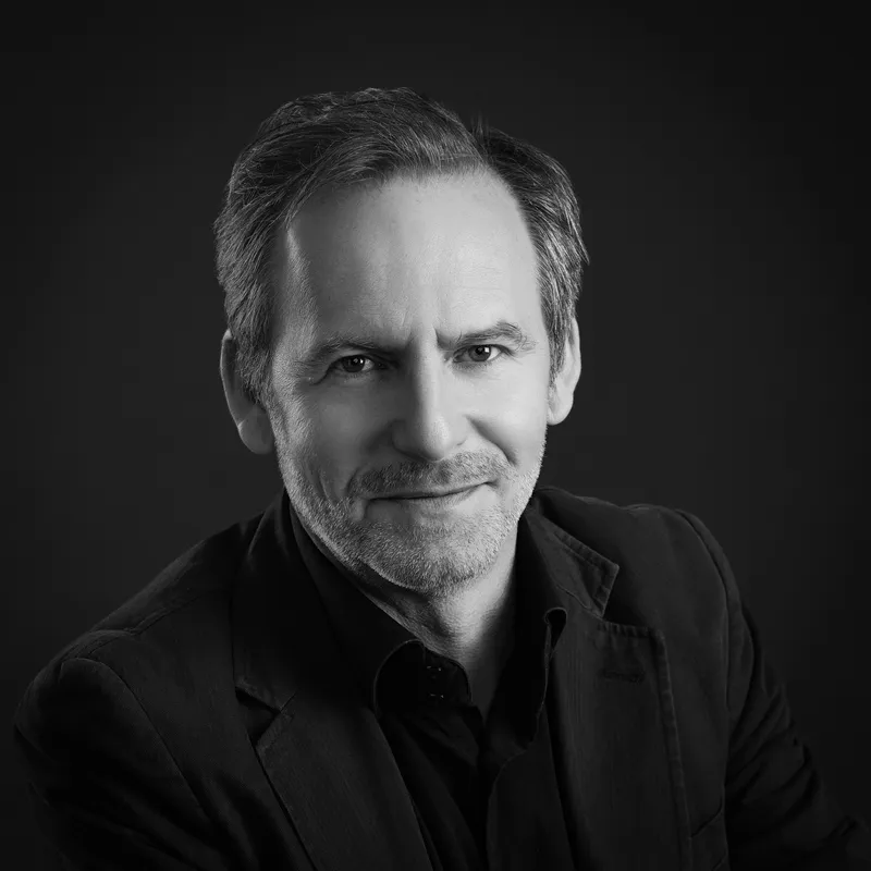 Portrait corporate noir et blanc d’un chef d’entreprise exprimant confiance et expertise dans un environnement studio.