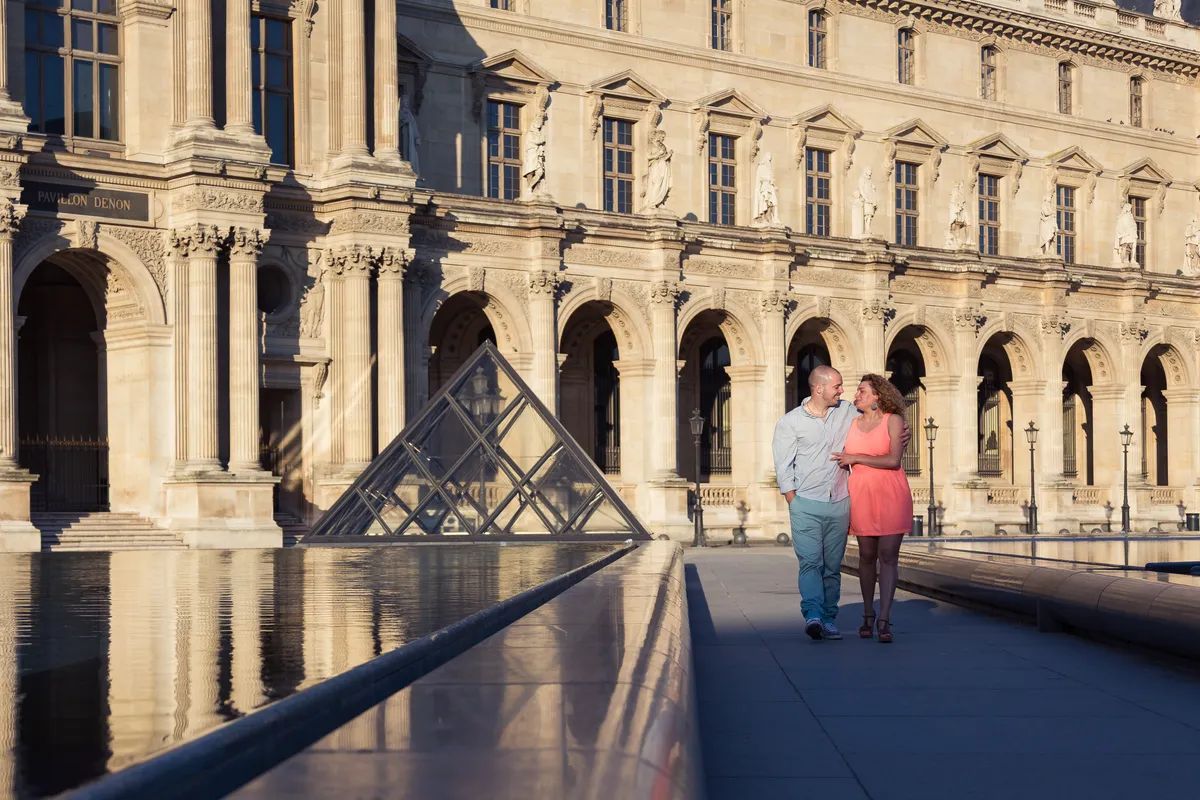 Couple marchant devant le musée du Louvre pendant une séance photo romantique à Paris.
