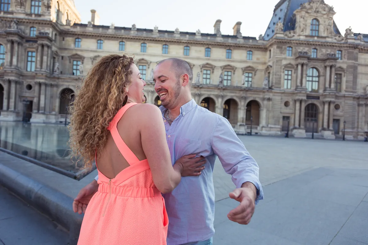 Couple échangeant un regard complice pendant une séance photo de couple au Louvre.
