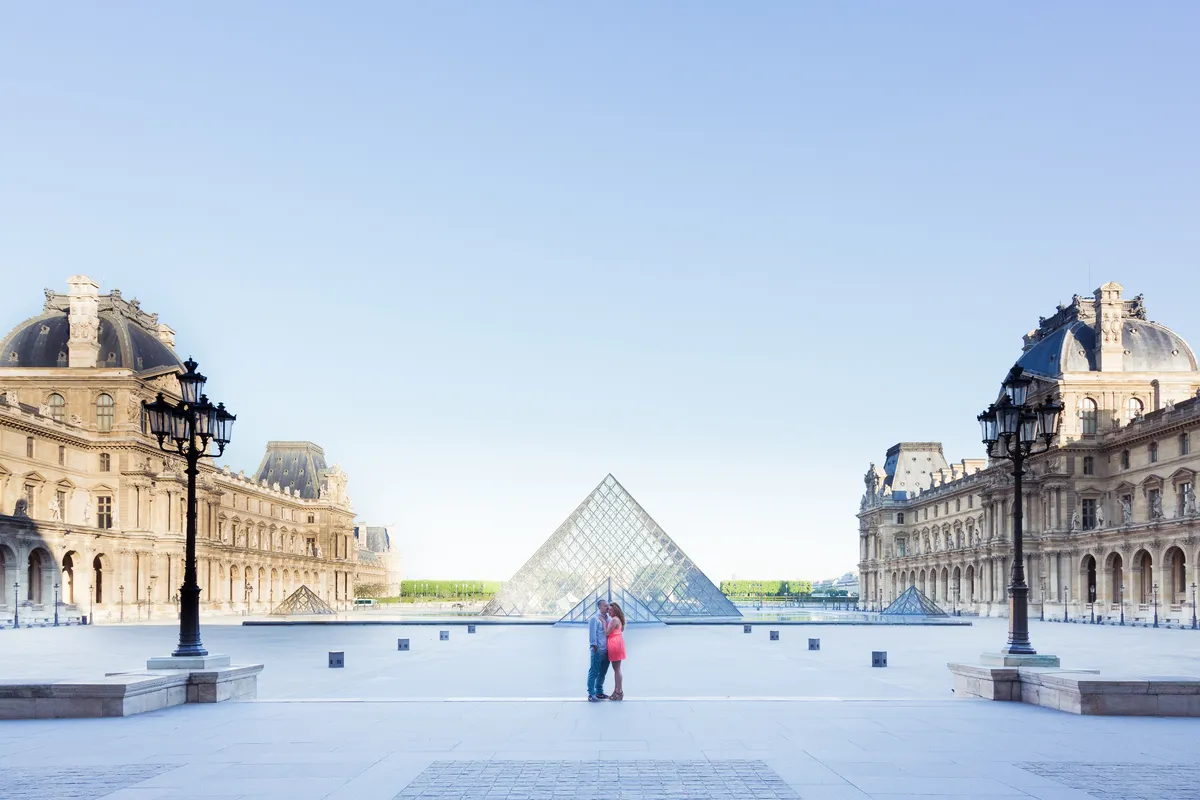Couple devant la pyramide du Louvre au petit matin lors d’une séance photo à Paris.