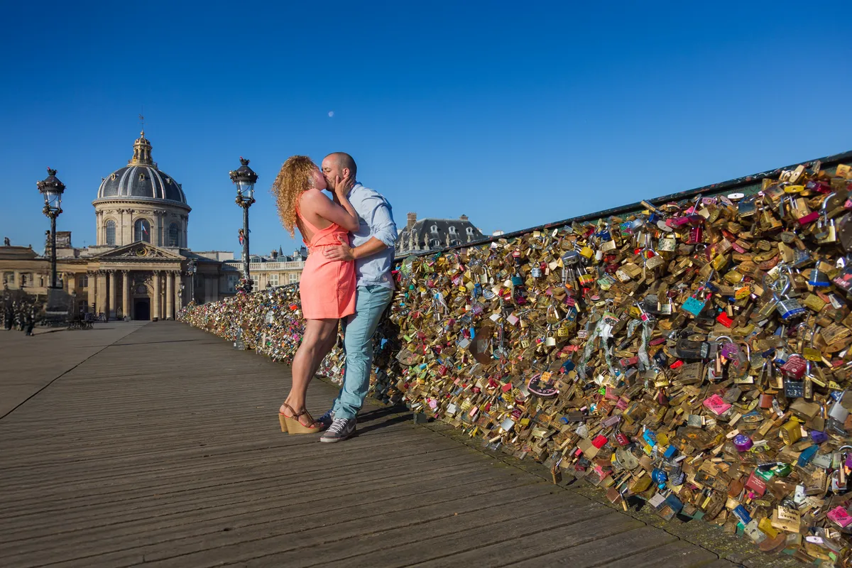 Couple s’embrassant sur le Pont des Arts pendant une séance photo romantique à Paris.
