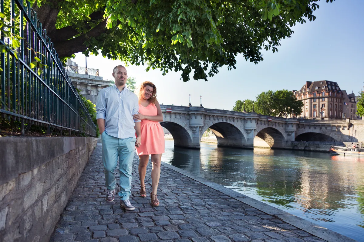 Couple se promenant le long de la Seine pendant une séance engagement à Paris.