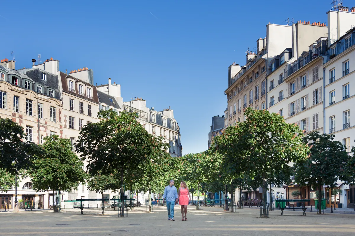 Couple marchant dans une place parisienne pendant une séance photo engagement.