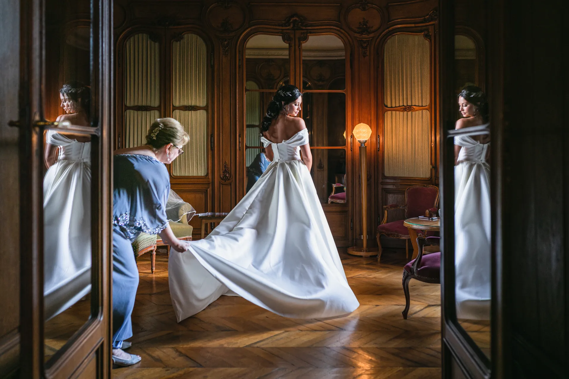 Une mère ajustant la robe de mariée de sa fille, reflétées dans les miroirs de l'Abbaye des Vaux de Cernay