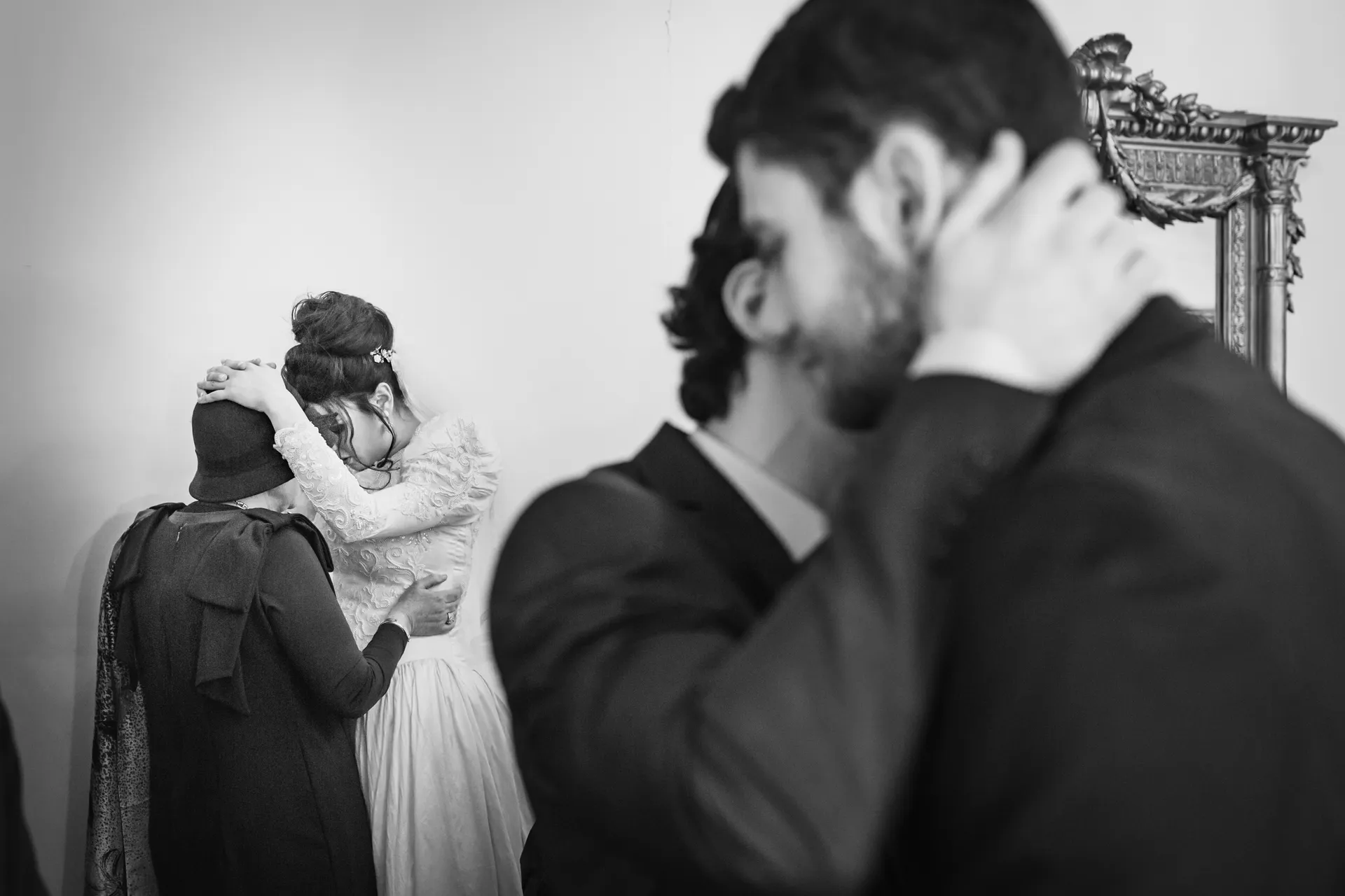 Mariée dans les bras de sa grand-mère pendant la bénédiction, le marié avec son frère en arrière-plan, cérémonie de mariage juif à Paris