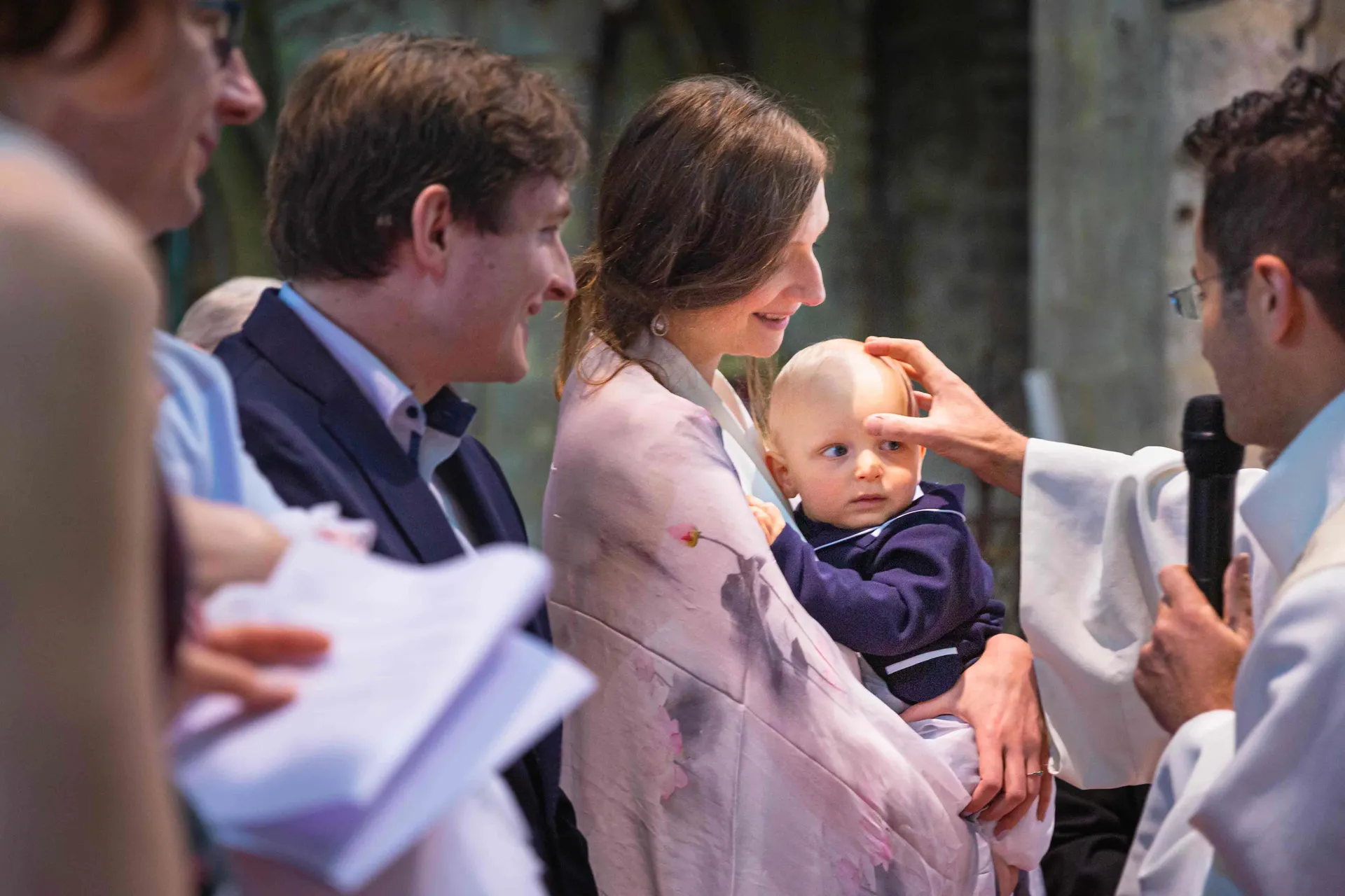 Parents et proches entourant un bébé lors d'une cérémonie de baptême dans une église du 3ᵉ arrondissement de Paris