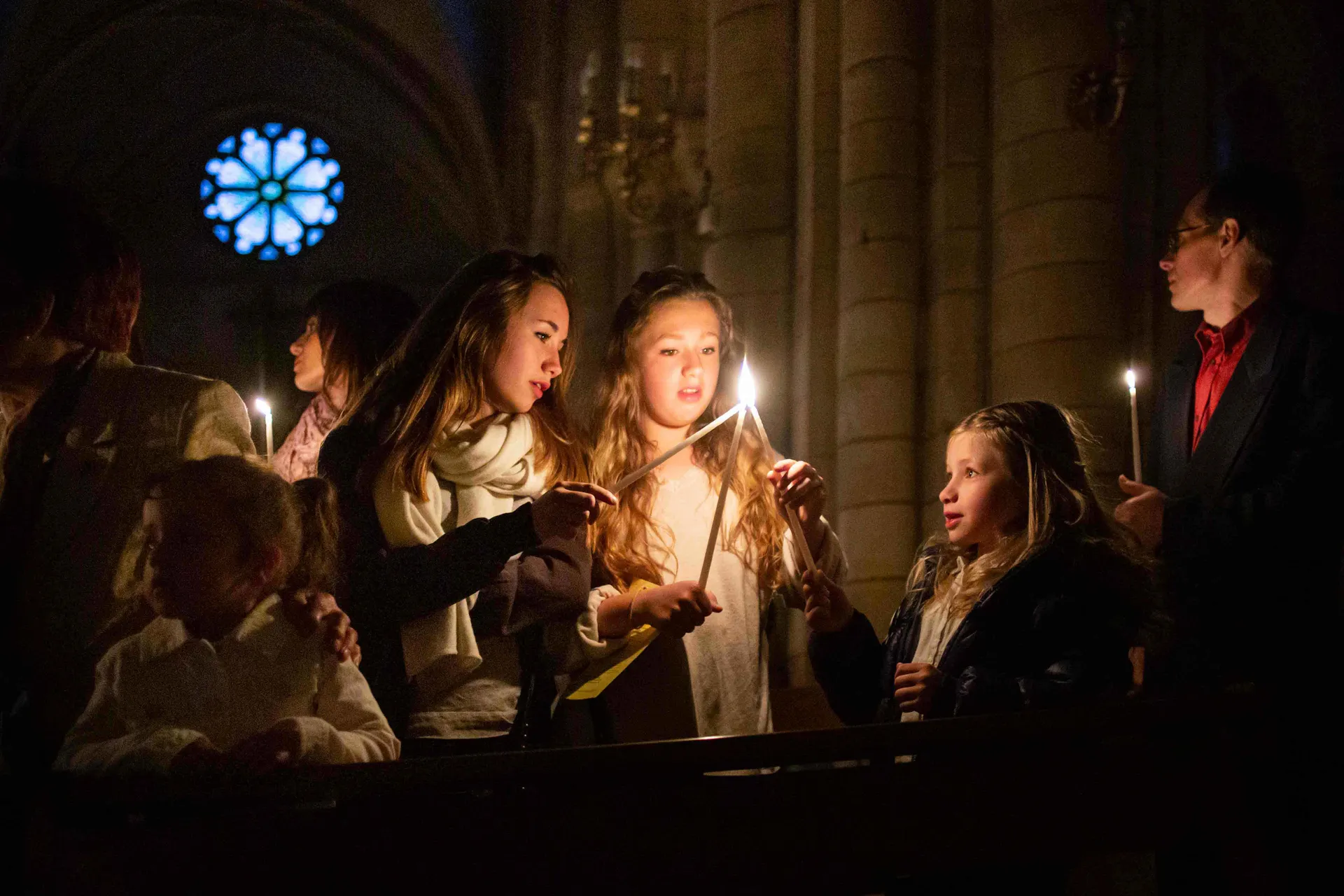 Famille réunie autour de bougies allumées lors d'une veillée de baptême à la basilique de Longpont-sur-Orge