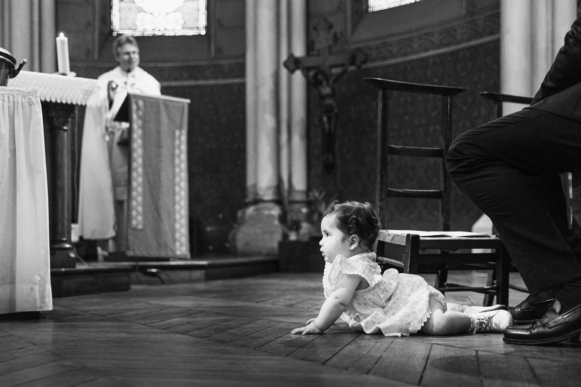 Bébé marchant à quatre pattes devant le prêtre pendant la cérémonie de baptême dans une église à Paris