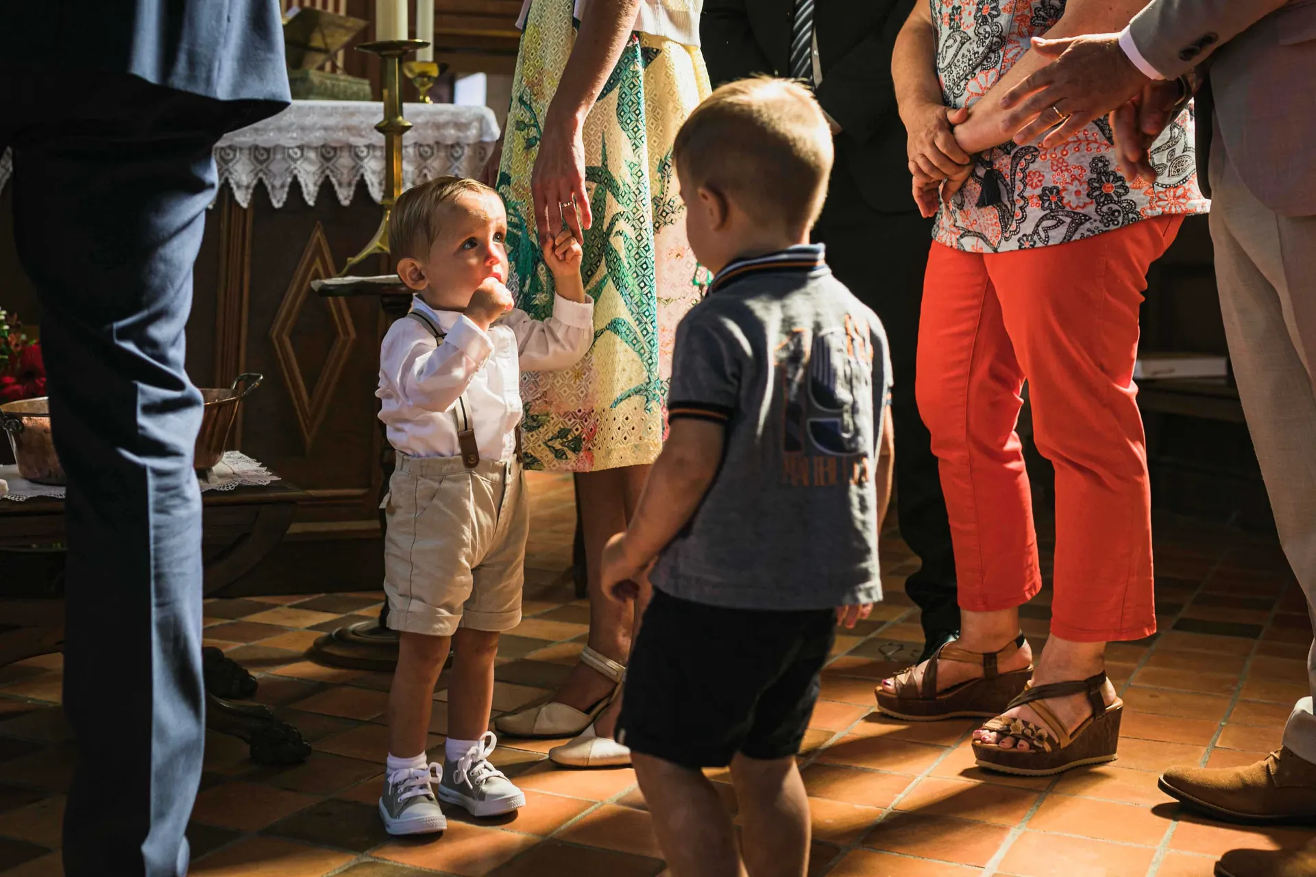 Enfant tenant la main de sa mère, éclairé par un rayon de soleil juste avant son baptême dans une église à Paris