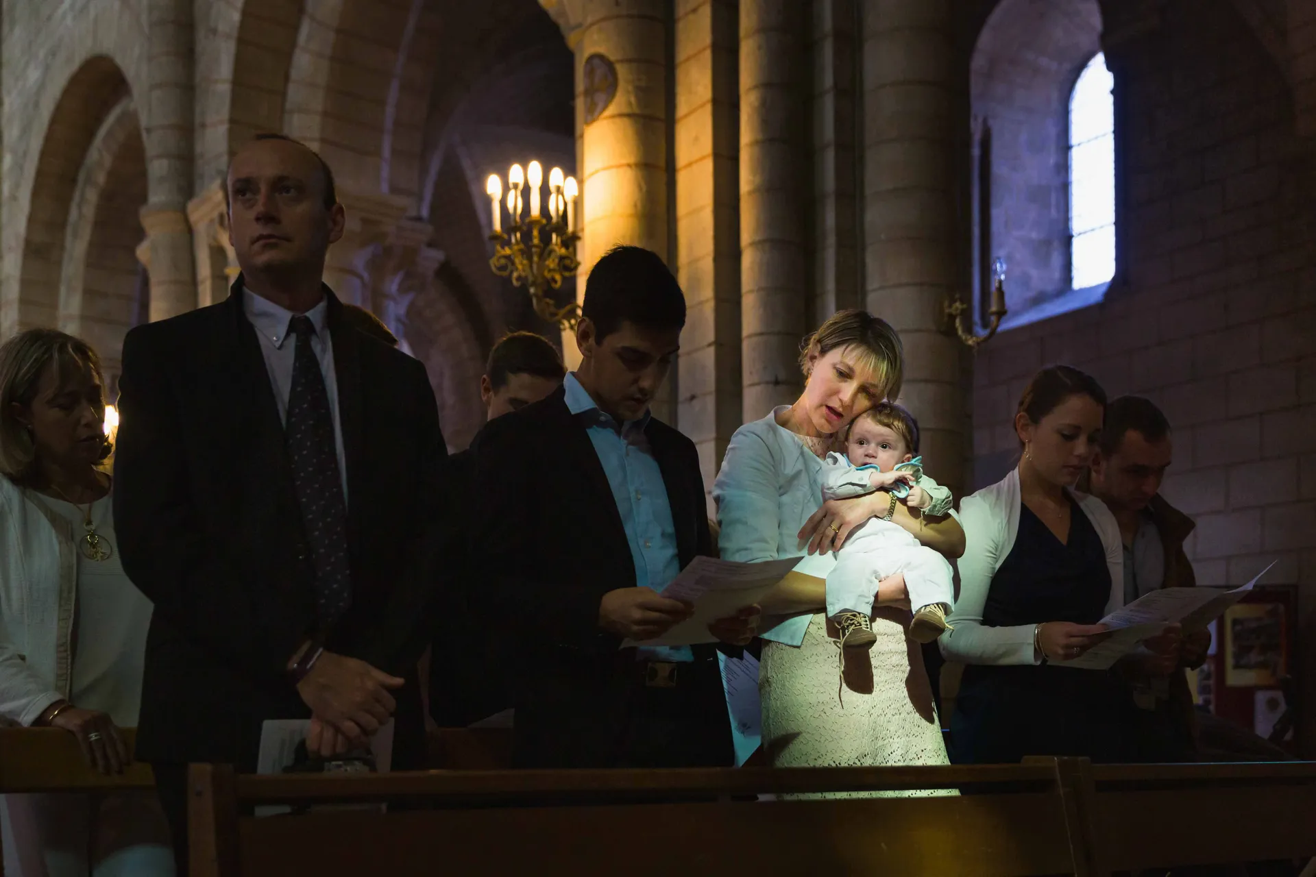 Rayon de lumière naturelle éclairant un petit garçon et sa mère lors d'un baptême dans une église à Paris