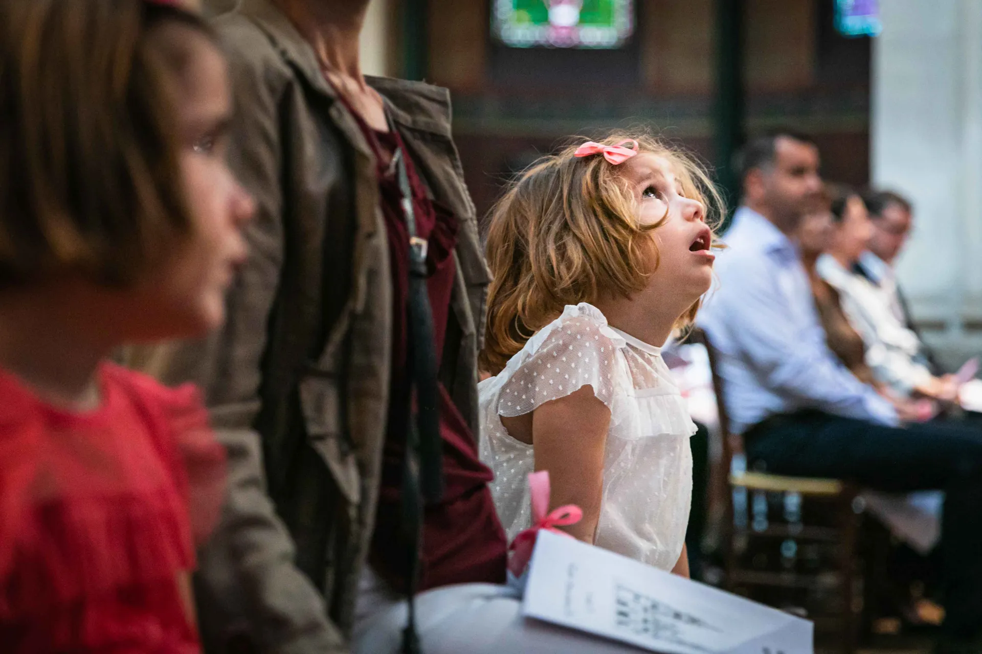 Petite fille rêveuse regardant la voûte étoilée d'une église lors d'un baptême à Paris