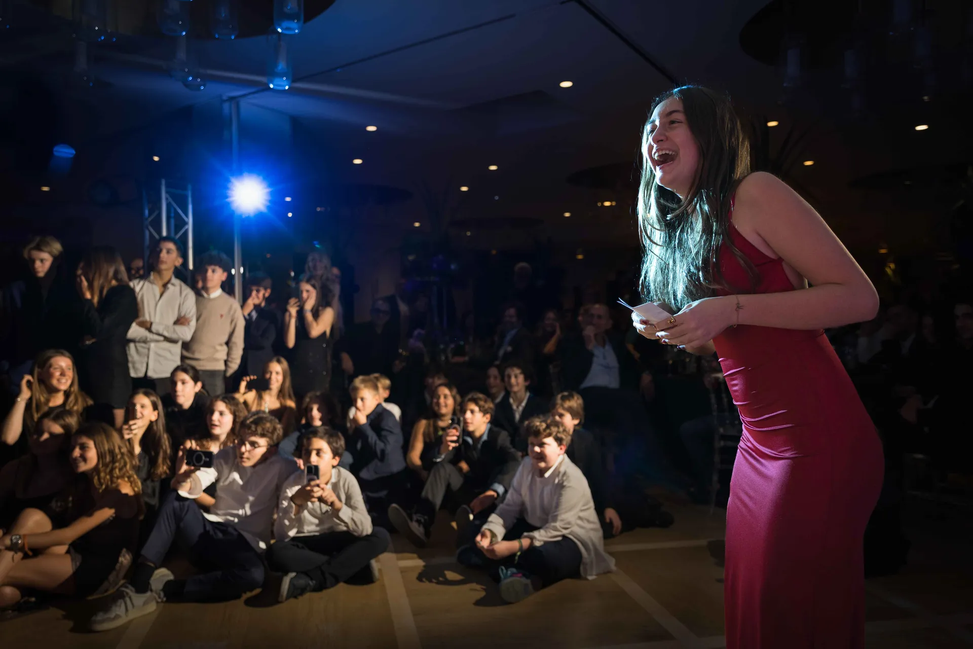 Jeune fille micro en main, animant la soirée devant les invités assis au sol, Bat-Mitzvah à Paris