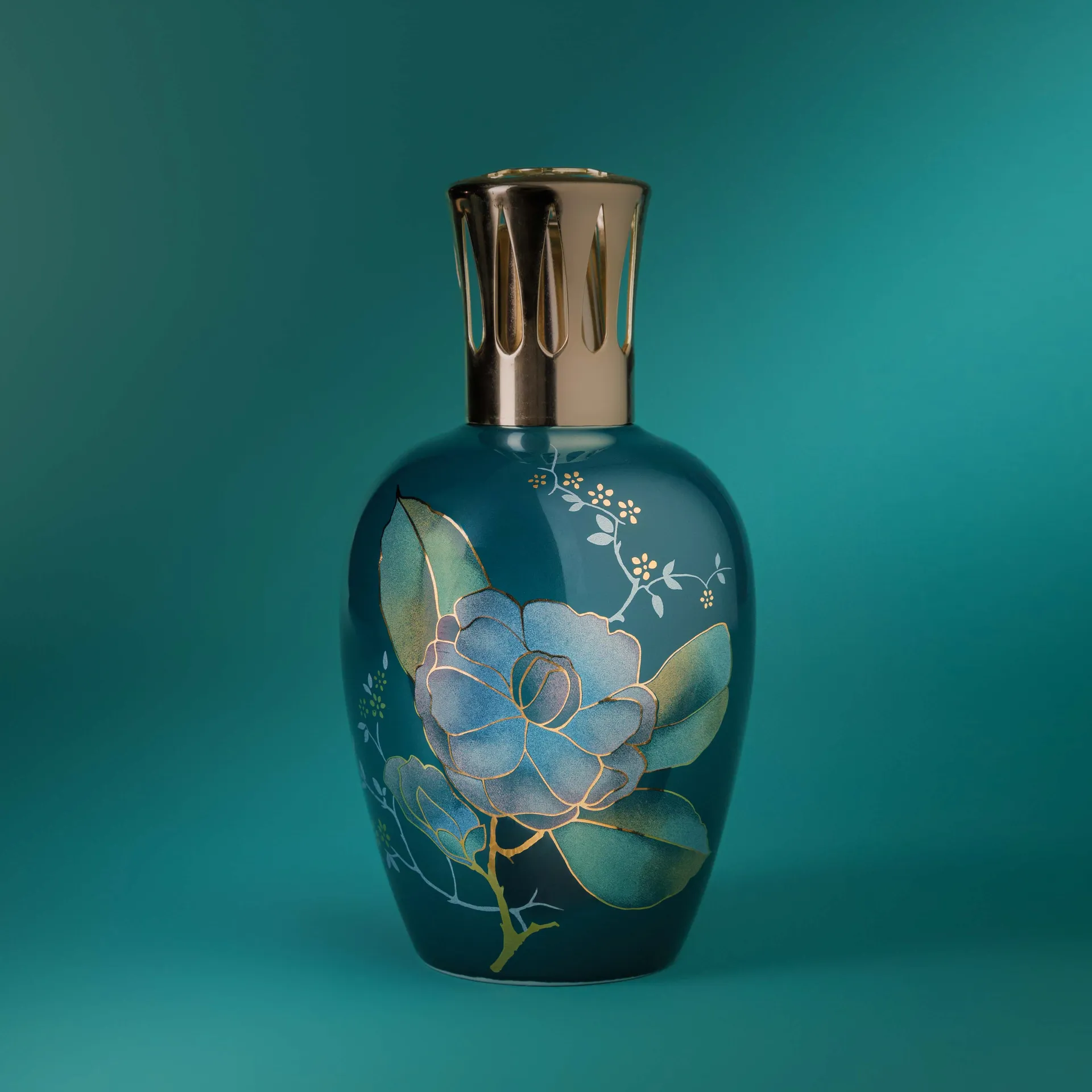Photographie produit d'une lampe Berger à pétrole, décor floral peint, fond bleu-vert